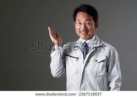 Asian middle aged worker pointing side in black background