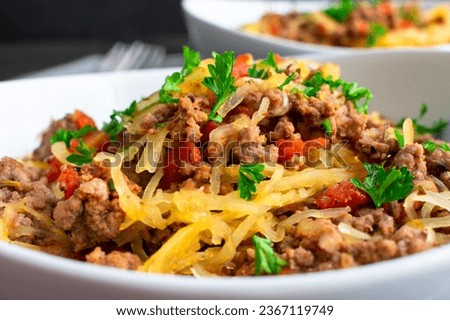 Spaghetti Squash Bolognese Garnished with Parsley Close-up: Bowl of spaghetti squash served with a ground beef and tomato sauce Royalty-Free Stock Photo #2367119749