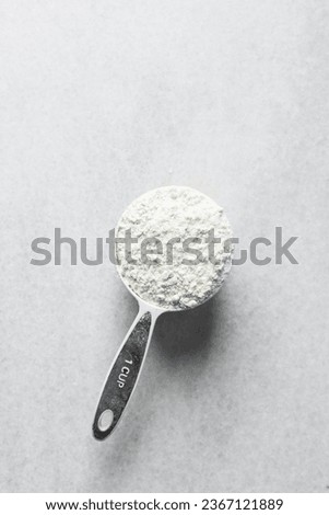 Top view of all purpose flour in a white plastic measuring cup, baking flour in a white measuring cup Royalty-Free Stock Photo #2367121889