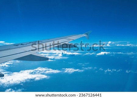 A breathtaking capture of an airplane's right wing soaring gracefully above a sea of clouds and a vast expanse of clear blue sky. Embodies the thrill of flight and the vastness of the sky.
