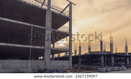 New construction site with crane and mechanical equipments on sunset background. Construction work building with yellow Evening light.