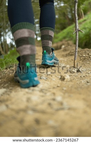 Detail of the feet and boots of a woman hiker, while walking along a trail, in the middle of nature Royalty-Free Stock Photo #2367145267