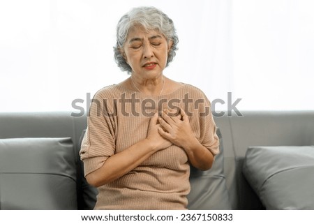 Elderly asian woman sitting on the couch, chest pain heart attact.
