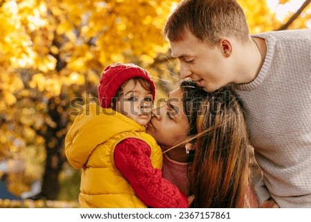 an international family with their child in the autumn park on a walk. Warm feelings and emotions Royalty-Free Stock Photo #2367157861