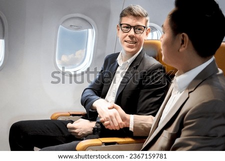 Businessman making handshake in comfortable seat inside airplane male passenger handshaking after good deal during business trip in aircraft cabin, businesspeople traveling with airline transportation Royalty-Free Stock Photo #2367159781