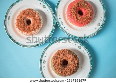 Several homemade donuts with the main topping of palm sugar combined with other toppings served on a plate and a turquoise background. Simple photo concept of homemade donut snack