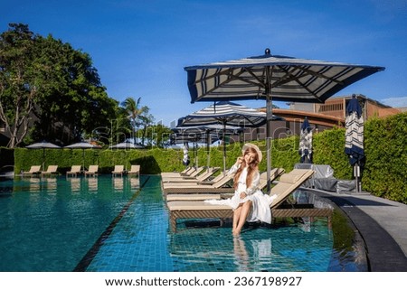 Serene summer scene. Female in white dress, relaxes poolside at modern Thai villa resort. Tropical beauty of paradise, lush green landscape and azure waters, ultimate relaxation for perfect vacation.