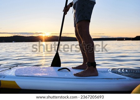 Male legs on a paddle board.