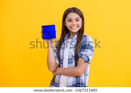Portrait of happy teen girl with birthday gift isolated on yellow. teen girl celebrate birthday with present in studio. teen girl holding birthday present box on background. birthday teen girl posing