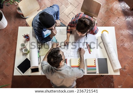 Working Group. Three young architects working on a project at a table in the study Royalty-Free Stock Photo #236721541