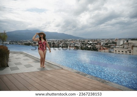 Overweight young asian woman wearing swimsuit relaxing in the pool Happy plus size woman cheery funny Vacation Traveling in summer.
