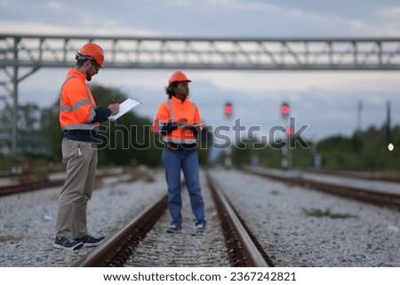 Male and Female Railway engineers with orange safety jackets check the railway Royalty-Free Stock Photo #2367242821
