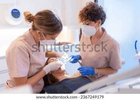 Dentist and assistant examining the mouth of a patient lying on the chair of a clinic Royalty-Free Stock Photo #2367249179