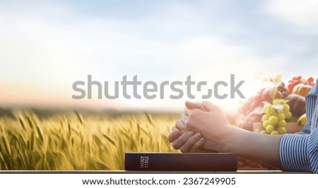 Abundant crops and fruits in a barley field, a praying Christian and a Bible book, and Thanksgiving and Thanksgiving decoration background concept
