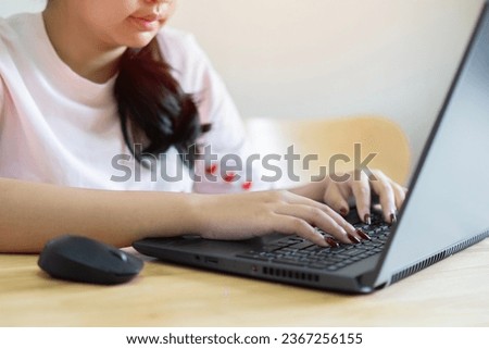 Shot of confident young Asian woman worker sit at office table by laptop search data browse corporate network for business news. Selecitve focus on hand.