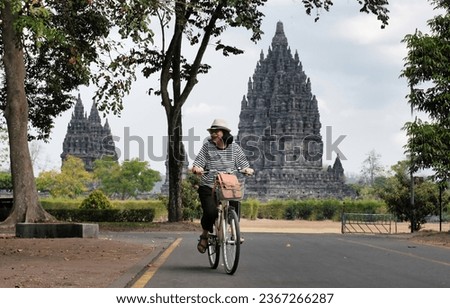 Asian female tourist riding a rental bicycle at Prambanan Temple national park Royalty-Free Stock Photo #2367266287