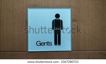 The sign for the men's toilet is in the shape of a box with a gray background made of acrylic with a vector symbol for men.