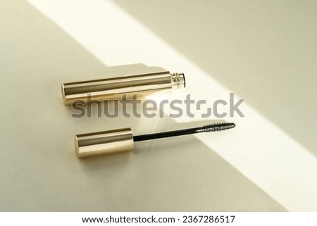 Mascara brush lies next to an open tube, on a beige background with shadows from sunlight. Copy space place for text cosmetic background Royalty-Free Stock Photo #2367286517