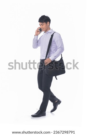 Full body 
portrait of young businessman in striped shirt using cellphone, with handbag standing posing white background
