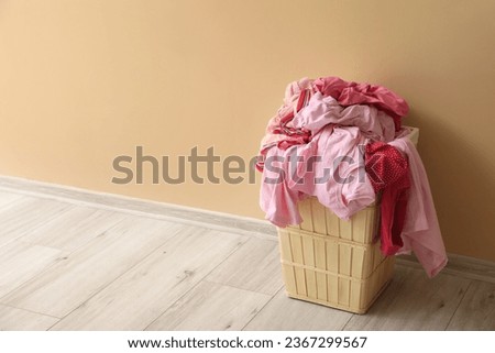 Basket with dirty clothes near beige wall