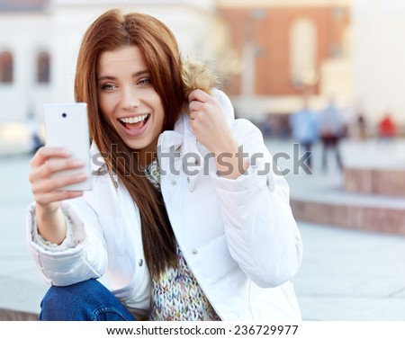 pretty young woman taking a picture on town. Smiling girl. Winter