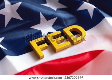 The Federal Reserve ( FED ) to control interest rates. Gold text FED on  USA flag background. American economy and business. Federal Reserve Bank Interest rates rise policy. World economy crisis.