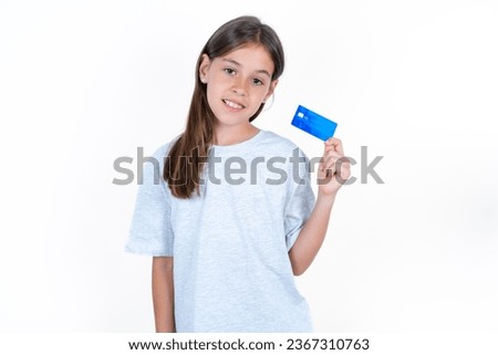 Photo of happy cheerful smiling positive young beautiful kid girl wearing wearing grey T-shirt recommend credit card
