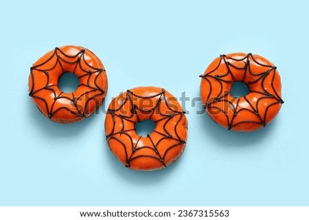 Tasty donuts for Halloween on blue background