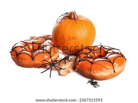 Tasty donuts for Halloween with pumpkin, spiders and leaves on white background