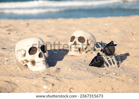 Skulls and skeleton hand for Halloween with stylish sunglasses on beach