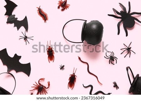 Halloween composition with candy bugs, cauldron and bats on pink background