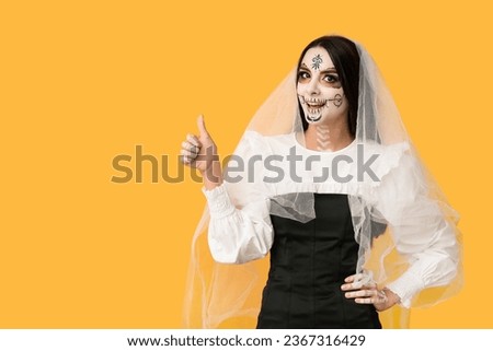 Beautiful young woman dressed as dead bride for Halloween party showing thumb-up gesture on yellow background