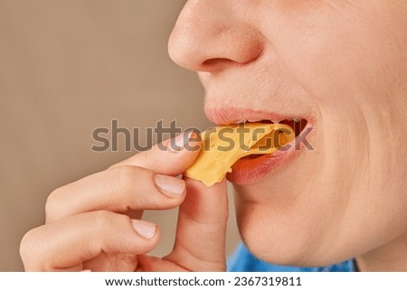 Close-up of a happy Caucasian woman holding a slice of cheese with her hand and biting it. Side view. Low angle view. Royalty-Free Stock Photo #2367319811