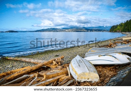 Driftwood and old boats on Davis Bay Beach. Sechelt, Sunshine Coast, British Columbia, Canada Royalty-Free Stock Photo #2367323655