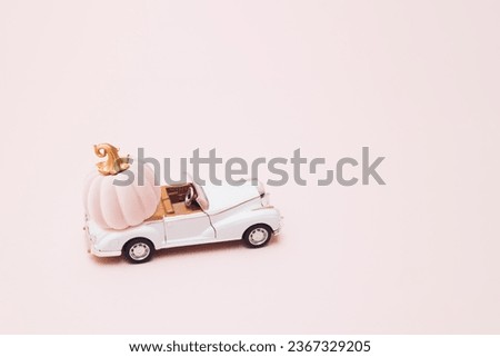 Old classic retro white convertible with pink pumpkin on trunk. Pink background.