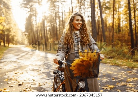 Happy young woman riding a bike, having fun in the autumn park. Concept of relaxation, nature. Active lifestyle. Royalty-Free Stock Photo #2367345157