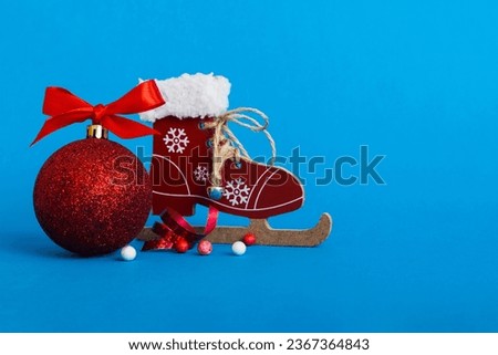 Christmas ball with skates on colored background. decoration bauble with ribbon bow with copy space.