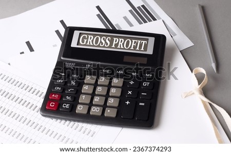 GROSS PROFIT text on calculator with chart on a grey background Royalty-Free Stock Photo #2367374293