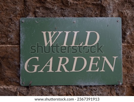 Wild garden sign, lettering in English. Light lettering on a dark background. United Kingdom