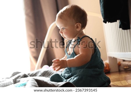 A 10 month old Caucasian baby girl playing in her room wearing a blue-green dress Royalty-Free Stock Photo #2367393145