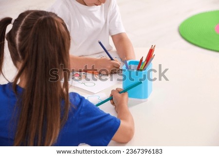Little children drawing pictures at desk in kindergarten, closeup