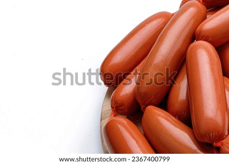 a lot of sausages with young green lettuce, garlic and peppercorns, on a wooden board, on a white background