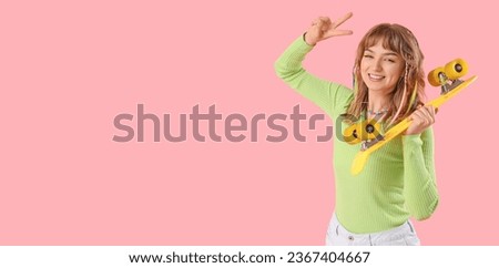 Happy teenage girl with skateboard showing victory gesture on pink background with space for text