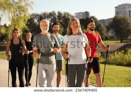 Group of happy people practicing Nordic walking with poles in park Royalty-Free Stock Photo #2367409405