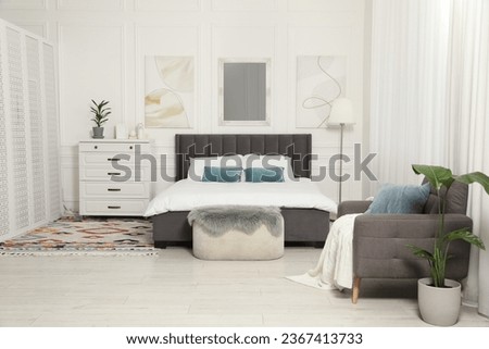 Stylish bedroom interior with large comfortable bed and armchair