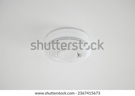 Image of simple plain fire alarm detector on the white ceiling