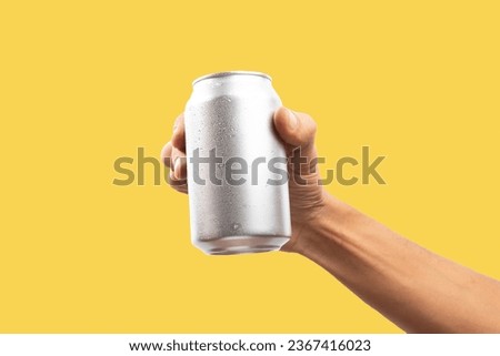 Man holding aluminum can on yellow background Royalty-Free Stock Photo #2367416023