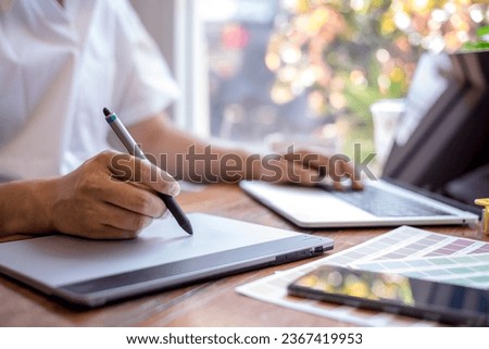 Young graphic designer using graphics tablet to do his work at desk