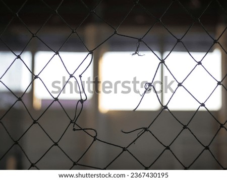 The futsal field's net with a hole in the middle is photographed up close