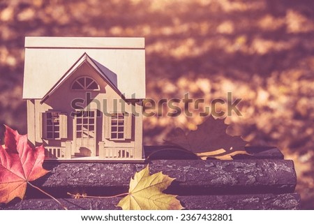 The symbol of the house stands among the fallen autumn leaves
